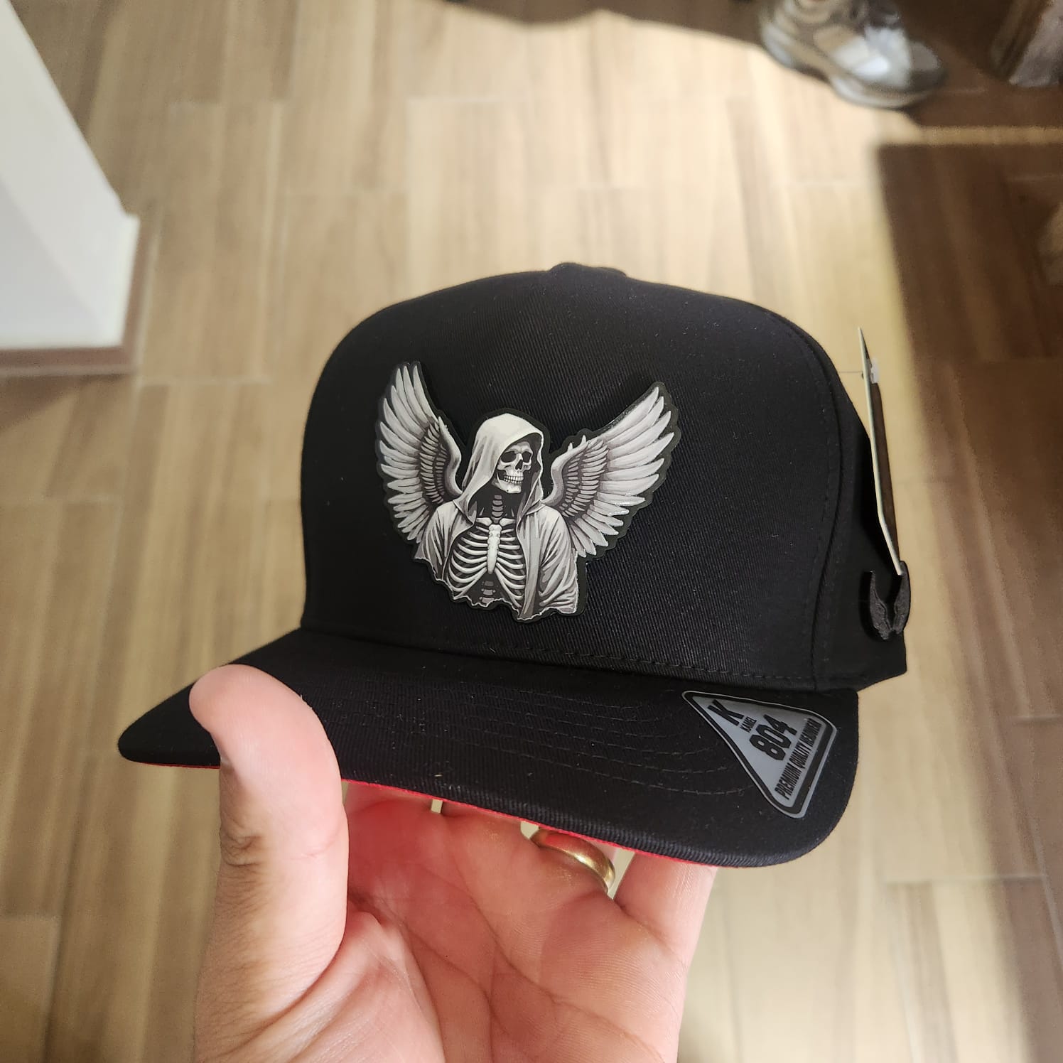 MUERTE CON ALAS GORRA NEGRA PLACA KAMEL